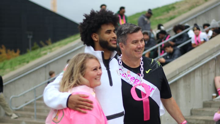 Oregon football quarterback Dante Moore poses with Men Wear Pink of Lane County ambassador James Conners and rally speaker April Brown during a breast cancer awareness rally at Autzen Stadium on Oct. 5, 2025.