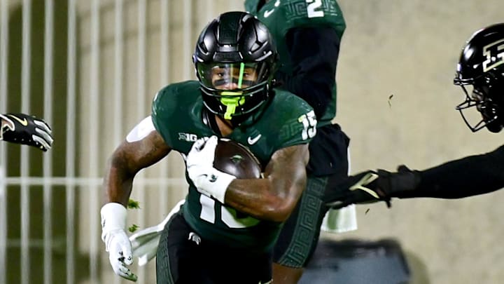 Nov 22, 2024; East Lansing, Michigan, USA;  Michigan State Spartans running back Kay'Ron Lynch-Adams (15) takes the ball from Michigan State Spartans quarterback Aidan Chiles (2) and runs through the line against the Purdue Boilermakers during the third quarter at Spartan Stadium. Mandatory Credit: Dale Young-Imagn Images