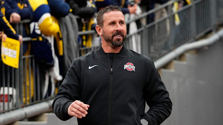 Ohio State Buckeyes offensive coordinator Brian Hartline laughs after hearing jeers as he walks onto the field prior to the NCAA football game against the Michigan Wolverines at Michigan Stadium in Ann Arbor, Mich. on Nov. 29, 2025.