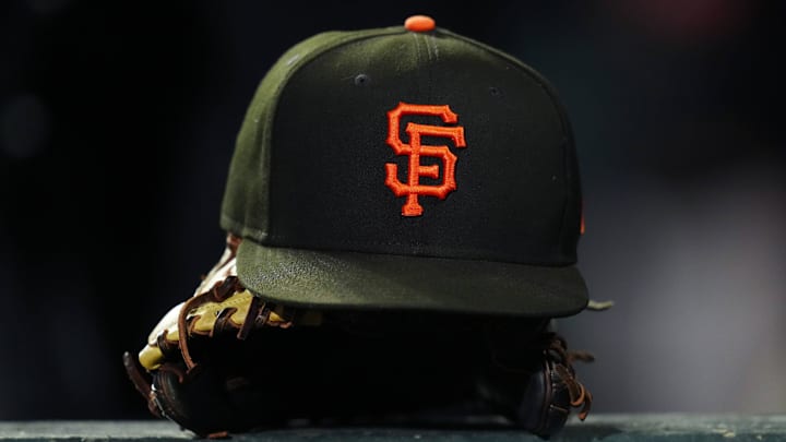 A San Francisco Giants cap and glove sits on a dugout railing.