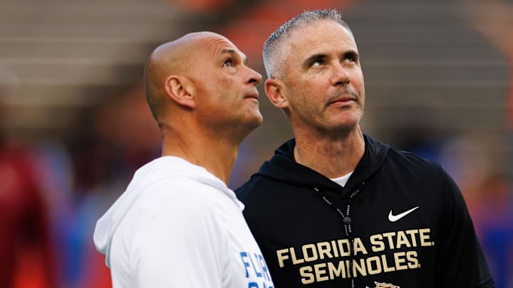 Nov 29, 2025; Gainesville, Florida, USA; Florida Gators interim head coach Billy Gonzales and Florida State Seminoles head coach Mike Norvell talk before the game at Ben Hill Griffin Stadium. Mandatory Credit: Matt Pendleton-Imagn Images