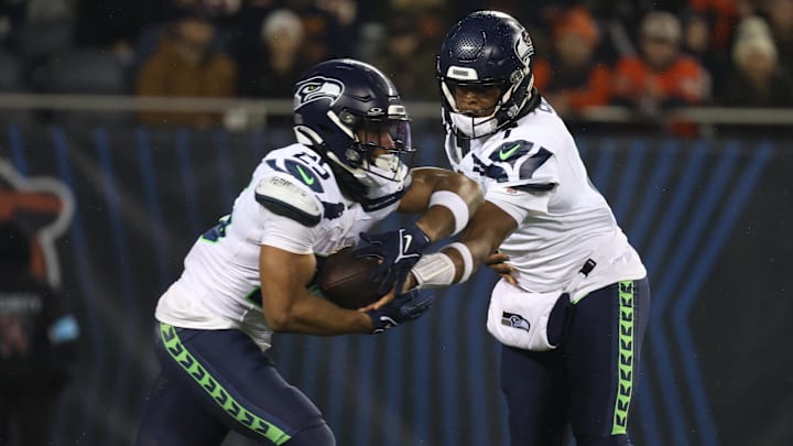 Dec 26, 2024; Chicago, Illinois, USA; Seattle Seahawks quarterback Geno Smith (7) hands the ball off to Seattle Seahawks running back Kenny McIntosh (25) during the second quarter against the Chicago Bears  at Soldier Field. Mandatory Credit: Talia Sprague-Imagn Images