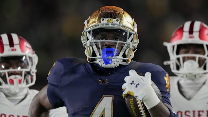 Notre Dame Fighting Irish running back Jeremiyah Love (4) scores a touchdown while being chased by Indiana Hoosiers defensive back D'Angelo Ponds (5) and Indiana Hoosiers defensive back Jamari Sharpe (22) during the first half of a game between the Indiana Hoosiers and the Notre Dame Fighting Irish in first round of the College Football Playoff on Friday, Dec. 20, 2024, in South Bend.