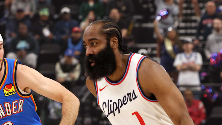 Mar 23, 2025; Inglewood, California, USA; LA Clippers guard James Harden (1) dribbles against Oklahoma City Thunder guard Alex Caruso (9) during the first quarter at Intuit Dome. Mandatory Credit: Jason Parkhurst-Imagn Images