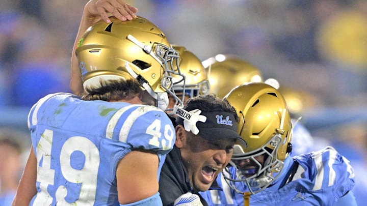 Nov 8, 2024; Pasadena, California, USA;   UCLA Bruins defensive coordinator Ikaika Malloe, center, celebrates with linebacker Carson Schwesinger (49) defensive back Jaylin Davies (6) after an interception in the second half against the Iowa Hawkeyes at the Rose Bowl. Mandatory Credit: Jayne Kamin-Oncea-Imagn Images