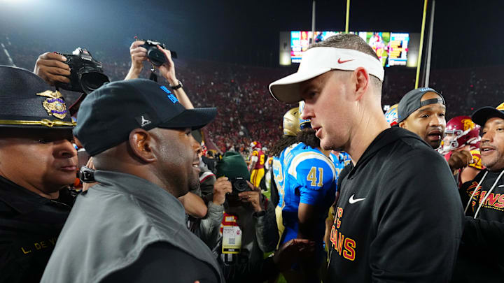 Nov 29, 2025; Los Angeles, California, USA; UCLA Bruins interim coach Tim Skipper (left) shakes hands with Southern California Trojans head coach Lincoln Riley after the game at United Airlines Field at Los Angeles Memorial Coliseum.