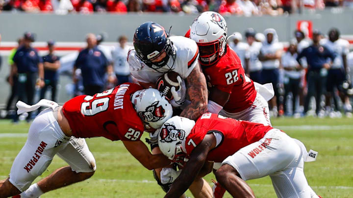 Sep 6, 2025; Raleigh, North Carolina, USA; Virginia Cavaliers tight end Sage Ennis (0) is tackled by North Carolina State Wolfpack safety Brody Barnhardt (29), cornerback Brian Nelson II (7) and cornerback Jackson Vick (22) during the first half of the game at Carter-Finley Stadium. Mandatory Credit: Jaylynn Nash-Imagn Images Sep 6, 2025; Raleigh, North Carolina, USA; Virginia Cavaliers tight end Sage Ennis (0) is tackled by North Carolina State Wolfpack safety Brody Barnhardt (29), cornerback Brian Nelson II (7) and cornerback Jackson Vick (22) during the first half of the game at Carter-Finley Stadium. Mandatory Credit: Jaylynn Nash-Imagn Images