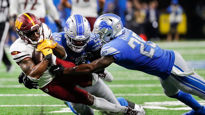 Former Lions linebacker Chris Board (49) and former safety Will Harris (25) tackle Commanders RB J.D. McKissic (23) 