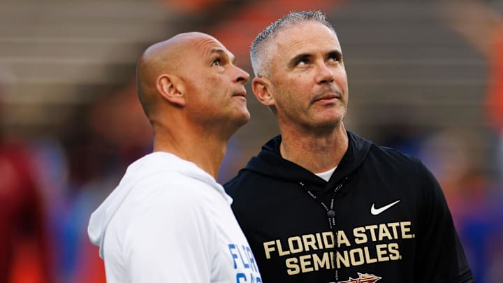 Nov 29, 2025; Gainesville, Florida, USA; Florida Gators interim head coach Billy Gonzales and Florida State Seminoles head coach Mike Norvell talk before the game at Ben Hill Griffin Stadium. Mandatory Credit: Matt Pendleton-Imagn Images
