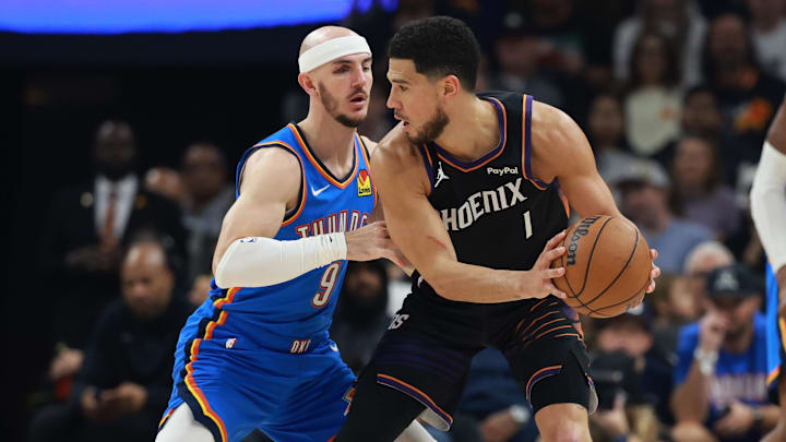 Jan 4, 2026; Phoenix, Arizona, USA; Phoenix Suns guard Devin Booker (1) against Oklahoma City Thunder guard Alex Caruso (9) in the first half at Mortgage Matchup Center. Mandatory Credit: Mark J. Rebilas-Imagn Images
