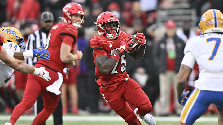 Nov 23, 2024; Louisville, Kentucky, USA;  Louisville Cardinals running back Isaac Brown (25) runs against Pittsburgh Panthers defensive lineman Jimmy Scott (44) during the first quarter at L&N Federal Credit Union Stadium. Mandatory Credit: Jamie Rhodes-Imagn Images