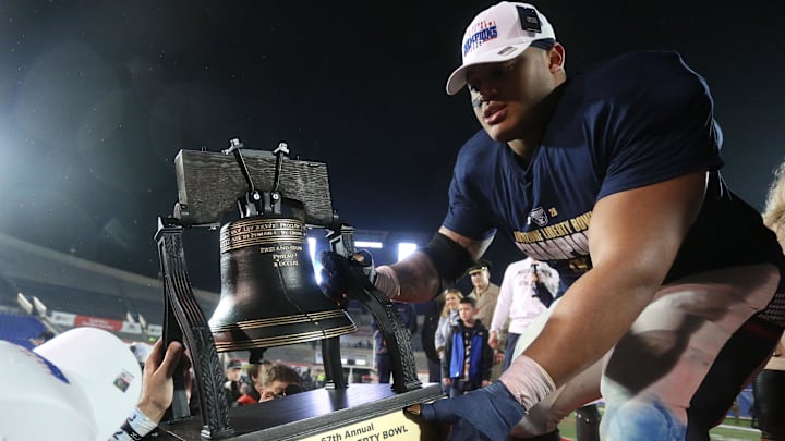 Jan 2, 2026; Memphis, TN, USA; Navy Midshipmen defensive lineman Landon Robinson (96) passes the Liberty Bell trophy off the stage after defeating the Cincinnati Bearcats in the Liberty Bowl at Simmons Bank Liberty Stadium. Mandatory Credit: Petre Thomas-Imagn Images