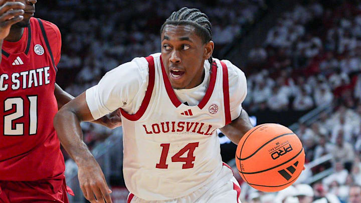Louisville Cardinals guard Adrian Wooley (14) drives as NC State Wolfpack guard Terrance Arceneaux (21) defends during ACC basketball February 9, 2026 in Louisville, Kentucky.