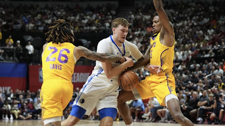 Jul 10, 2025; Las Vegas, NV, USA; Dallas Mavericks forward Cooper Flagg (32) dribbles against Los Angeles Lakers guard RJ Davis (26) and guard DaJaun Gordon (45) in the first quarter of their game at Thomas & Mack Center. Mandatory Credit: Candice Ward-Imagn Images