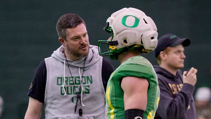 Oregon head coach Dan Lanning, left, talks to Oregon defensive back Dillon Thieneman during an open practice ahead of the Orange Bowl at the Moshofsky Center in Eugene, Oregon on Dec. 27, 2025.