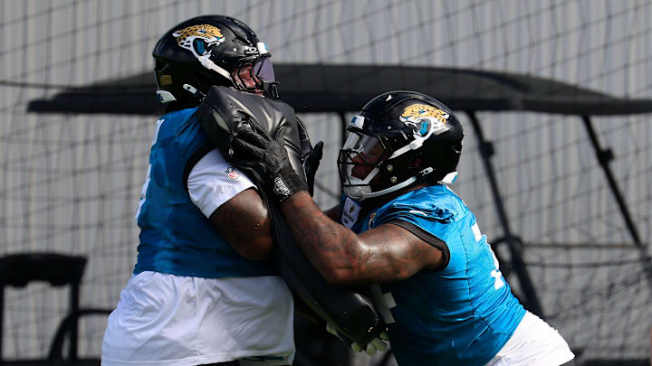 From left, Jacksonville Jaguars offensive tackle Anton Harrison (77) and lineman Fred Johnson (74) drill with blocking pads as offensive line coach Shaun Sarrett directs during an NFL training camp session at the Miller Electric Center, Friday, July 25, 2025, in Jacksonville, Fla. [Corey Perrine/Florida Times-Union]