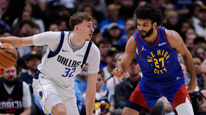 Dec 1, 2025; Denver, Colorado, USA; Dallas Mavericks forward Cooper Flagg (32) controls the ball as Denver Nuggets guard Jamal Murray (27) guards in the second quarter at Ball Arena.