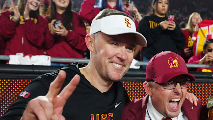 Nov 29, 2025; Los Angeles, California, USA; Southern California Trojans head coach Lincoln Riley (left) poses with Spirit of Troy marching band director James Vogel (center) and mascot Tommy Trojan after the game against the UCLA Bruins at United Airlines Field at Los Angeles Memorial Coliseum. Mandatory Credit: Kirby Lee-Imagn Images