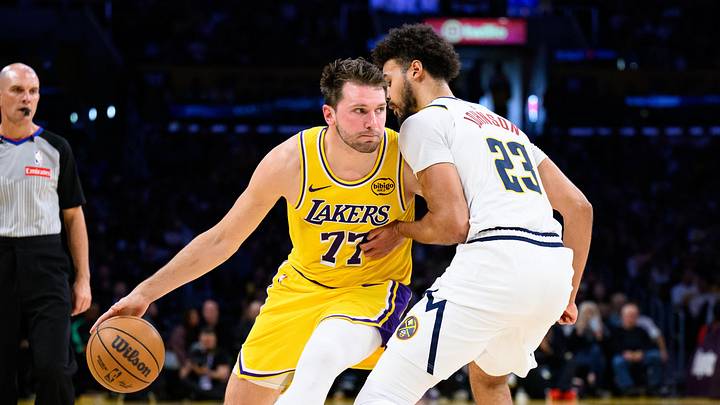 Mar 14, 2026; Los Angeles, California, USA; Los Angeles Lakers guard Luka Doncic (77) drives the ball while under pressure from Denver Nuggets forward Cameron Johnson (23) during the first half at Crypto.com Arena.