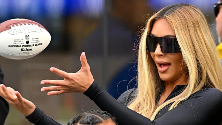 Dec 4, 2022; Inglewood, California, USA;  Kim Kardashian catches a football on the field as players warm up prior to a game between the Los Angeles Rams and the Seattle Seahawks at SoFi Stadium. Mandatory Credit: Jayne Kamin-Oncea-Imagn Images