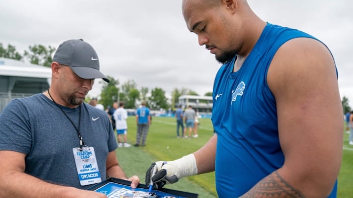 Detroit Lions OL Giovanni Manu signs an autograph after practice at team's Performance Center