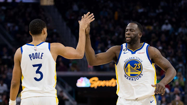 Former Golden State Warriors teammates, Jordan Poole and Draymond Green, high five during a game in 2023.