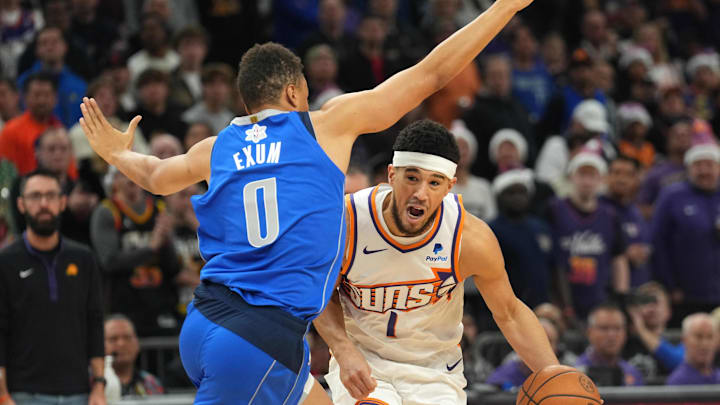 Dec 25, 2023; Phoenix, Arizona, USA; Phoenix Suns guard Devin Booker (1) dribbles against Dallas Mavericks guard Dante Exum (0) during the first half at Footprint Center. Mandatory Credit: Joe Camporeale-Imagn Images