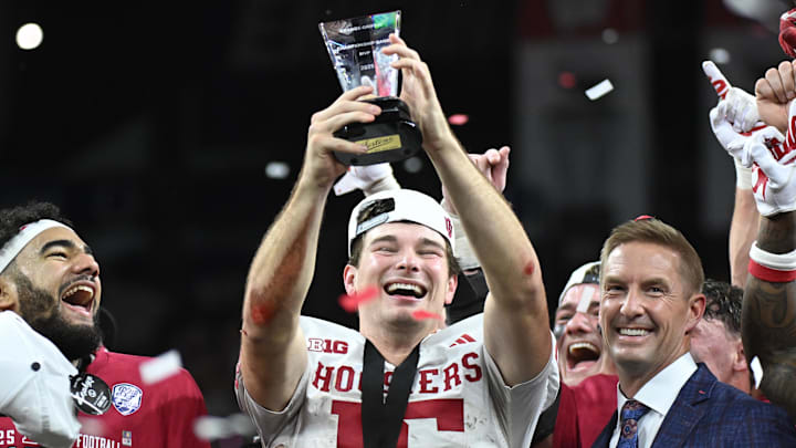 Dec 6, 2025; Indianapolis, IN, USA; Indiana Hoosiers quarterback Fernando Mendoza (15) celebrates with the MVP trophy after defeating the Ohio State Buckeyes in the 2025 Big Ten championship game at Lucas Oil Stadium. Mandatory Credit: Robert Goddin-Imagn Images Dec 6, 2025; Indianapolis, IN, USA; Indiana Hoosiers quarterback Fernando Mendoza (15) celebrates with the MVP trophy after defeating the Ohio State Buckeyes in the 2025 Big Ten championship game at Lucas Oil Stadium. Mandatory Credit: Robert Goddin-Imagn Images