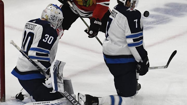 Dec 14, 2018; Chicago, IL, USA; Winnipeg Jets defenseman Ben Chiarot (7) blocks the puck in front of Chicago Blackhawks left wing Brandon Saad (20) as goaltender Laurent Brossoit (30) is nearby during the first period at United Center. Mandatory Credit: David Banks-Imagn Images