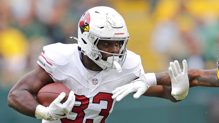 Arizona Cardinals running back Trey Benson (33) runs for a first down against Green Bay Packers cornerback Keisean Nixon (25) in the third quarter during their football game Sunday, October 13, 2024, at Lambeau Field in Green Bay, Wisconsin.