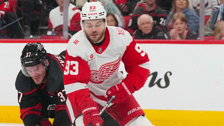 Dec 27, 2025; Raleigh, North Carolina, USA; Detroit Red Wings right wing Alex Debrincat (93) tries to control the puck against the check by Carolina Hurricanes right wing Andrei Svechnikov (37) during the second period at Lenovo Center.