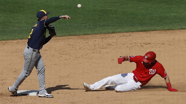 Aug 3, 2025; Washington, District of Columbia, USA; Milwaukee Brewers second baseman Brice Turang (2) turns a game-ending double play at second base ahead of a slide by Washington Nationals outfielder Jacob Young (30) at Nationals Park. 