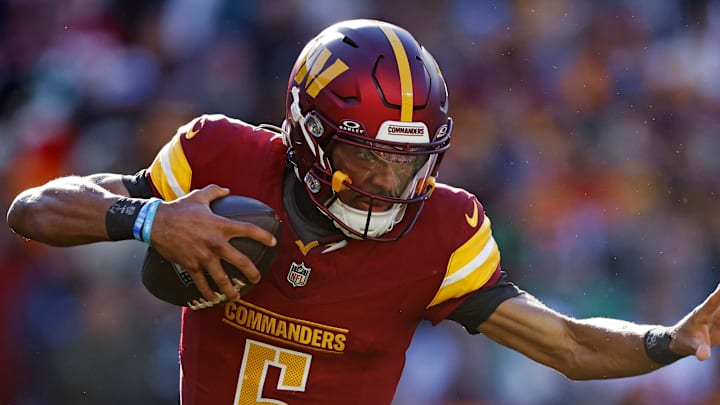 Dec 22, 2024; Landover, Maryland, USA; Washington Commanders quarterback Jayden Daniels (5) runs the ball against Philadelphia Eagles defensive tackle Jalen Carter (98) during the first quarter at Northwest Stadium. Mandatory Credit: Peter Casey-Imagn Images