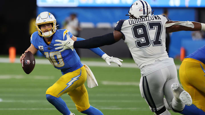Oct 16, 2023; Inglewood, California, USA;  Los Angeles Chargers quarterback Justin Herbert (10) runs away from Dallas Cowboys defensive tackle Osa Odighizuwa (97) during the third quarter at SoFi Stadium. 