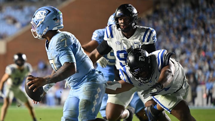 Nov 22, 2025; Chapel Hill, North Carolina, USA; North Carolina Tar Heels quarterback Gio Lopez (7) scrambles away from Duke Blue Devils defensive tackle Josiah Green (4) during the second half at Kenan Stadium. Mandatory Credit: William Howard-Imagn Images Nov 22, 2025; Chapel Hill, North Carolina, USA; North Carolina Tar Heels quarterback Gio Lopez (7) scrambles away from Duke Blue Devils defensive tackle Josiah Green (4) during the second half at Kenan Stadium. Mandatory Credit: William Howard-Imagn Images