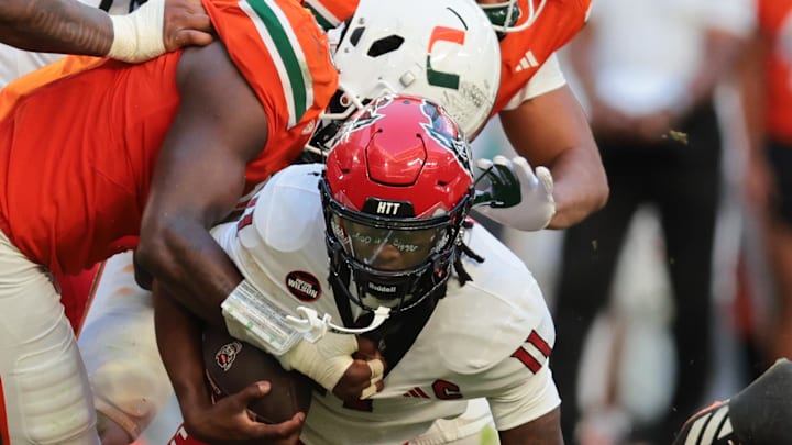 Nov 15, 2025; Miami Gardens, Florida, USA; NC State Wolfpack quarterback CJ Bailey (11) is tackled by Miami Hurricanes defensive lineman Armondo Blount (18) during the second quarter at Hard Rock Stadium. Mandatory Credit: Sam Navarro-Imagn Images