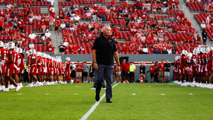 Aug 29, 2024; Raleigh, North Carolina, USA; North Carolina State Wolfpack head coach Dave Doeren between his players before the first half of the game against Western Carolina Catamounts at Carter-Finley Stadium. Mandatory Credit: Jaylynn Nash-Imagn Images