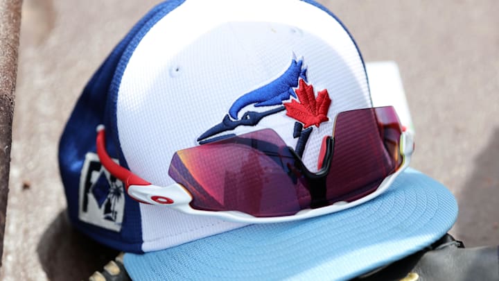 Mar 1, 2025; North Port, Florida, USA;  A detail view of a Toronto Blue Jays hat , sunglasses and glove laying in the dugout against the Atlanta Braves at CoolToday Park.