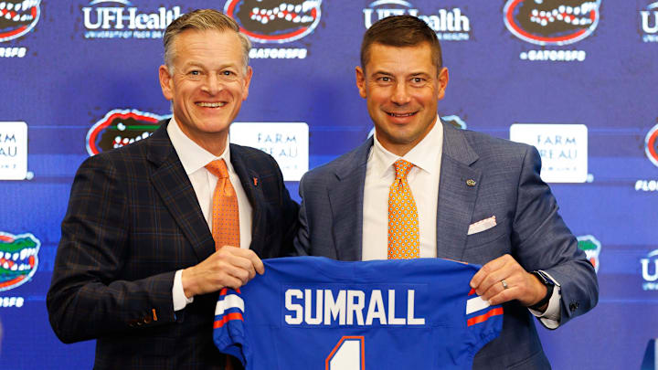Florida Gators athletic director Scott Stricklin and Florida Gators head coach Jon Sumrall pose with a Florida Gators jersey during the press conference.