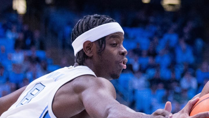 Dec 16, 2025; Chapel Hill, North Carolina, USA; ETSU Buccaneers guard Brian Taylor (11) drives between North Carolina Tar Heels forward Caleb Wilson (8) and guard Derek Dixon (3) during the first half at Dean E. Smith Center. Mandatory Credit: Scott Kinser-Imagn Images