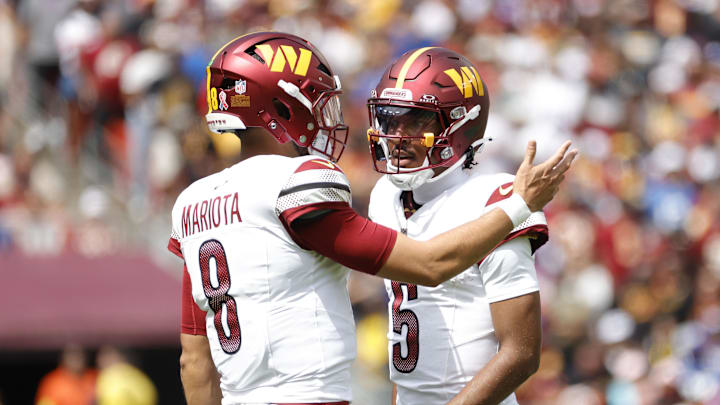 Washington Commanders quarterback Jayden Daniels (5) talks to Commanders quarterback Marcus Mariota (8).
