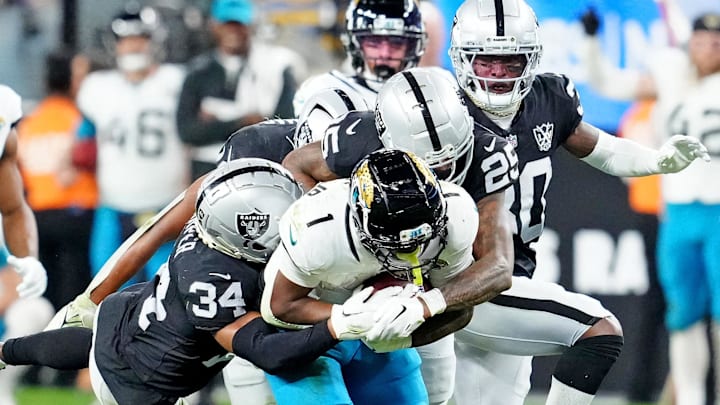 Dec 22, 2024; Paradise, Nevada, USA; Jacksonville Jaguars running back Travis Etienne Jr. (1) is tackled by Las Vegas Raiders safety Thomas Harper (34) and cornerback Decamerion Richardson (25) during the fourth quarter at Allegiant Stadium. Mandatory Credit: Stephen R. Sylvanie-Imagn Images Dec 22, 2024; Paradise, Nevada, USA; Jacksonville Jaguars running back Travis Etienne Jr. (1) is tackled by Las Vegas Raiders safety Thomas Harper (34) and cornerback Decamerion Richardson (25) during the fourth quarter at Allegiant Stadium. Mandatory Credit: Stephen R. Sylvanie-Imagn Images