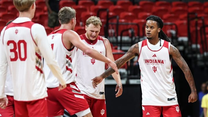 Indiana basketball guard Lamar Wilkerson high-fives teammate Trent Sisley, standing between Tucker DeVries and Ian Stephens.