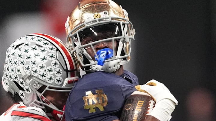 Notre Dame Fighting Irish running back Jeremiyah Love (4) is tackled by Ohio State Buckeyes defensive end JT Tuimoloau (44) in the CFP National Championship