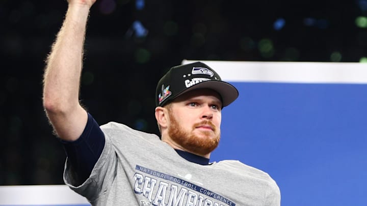 Jan 25, 2026; Seattle, WA, USA; Seattle Seahawks quarterback Sam Darnold (14) celebrates with the trophy on the podium after defeating the Los Angeles Rams in the 2026 NFC Championship Game at Lumen Field. 