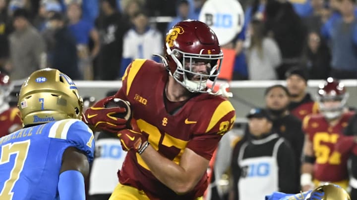 Nov 23, 2024; Pasadena, California, USA; USC Trojans tight end Lake McRee (87) runs a pass between UCLA Bruins defensive back K.J. Wallace (7) and defensive back Bryan Addison (4) during the second quarter at Rose Bowl. Mandatory Credit: Robert Hanashiro-Imagn Images
