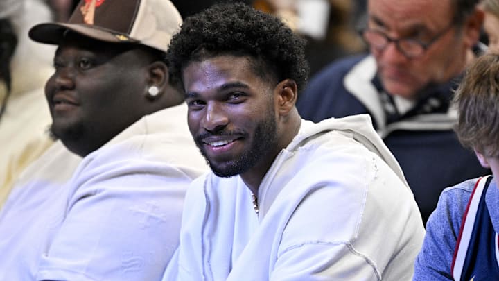 Jan 14, 2025; Dallas, Texas, USA; Colorado Buffaloes quarterback Shedeur Sanders smiles as he watches the game between the Dallas Mavericks and the Denver Nuggets during the second quarter at the American Airlines Center. Mandatory Credit: Jerome Miron-Imagn Images