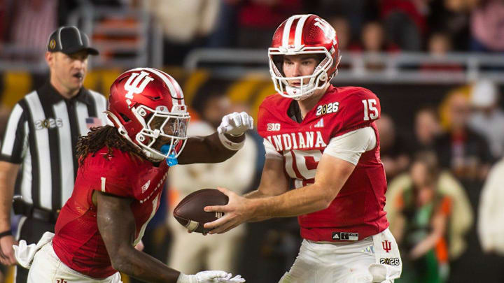 Indiana's Fernando Mendoza (15) hands the ball to Roman Hemby (1) as Miami's Rueban Bain Jr. (4) closes in during the College Football Playoff National Championship college football game at Hard Rock Stadium in Miami Gardens on Monday, Jan. 19, 2026.