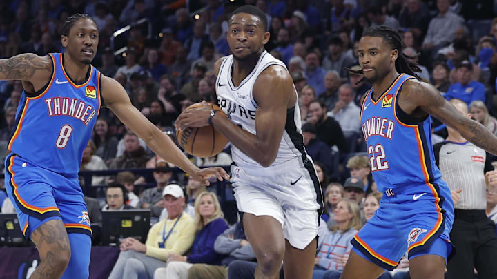 Jan 13, 2026; Oklahoma City, Oklahoma, USA; San Antonio Spurs guard De'aaron Fox (4) drives between Oklahoma City Thunder guard/forward Jalen Williams (8) and guard Cason Wallace (22) during the second quarter at Paycom Center. Mandatory Credit: Alonzo Adams-Imagn Images