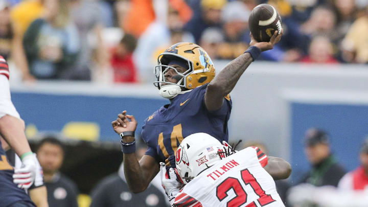 Sep 27, 2025; Morgantown, West Virginia, USA; West Virginia Mountaineers quarterback Khalil Wilkins (14) throws a pass while hit by Utah Utes safety Nate Tilmon (21) during the third quarter at Milan Puskar Stadium. Mandatory Credit: Ben Queen-Imagn Images Sep 27, 2025; Morgantown, West Virginia, USA; West Virginia Mountaineers quarterback Khalil Wilkins (14) throws a pass while hit by Utah Utes safety Nate Tilmon (21) during the third quarter at Milan Puskar Stadium. Mandatory Credit: Ben Queen-Imagn Images